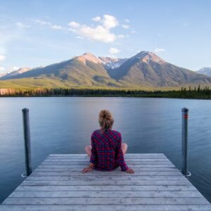 woman relaxing on jetty looking at mountains