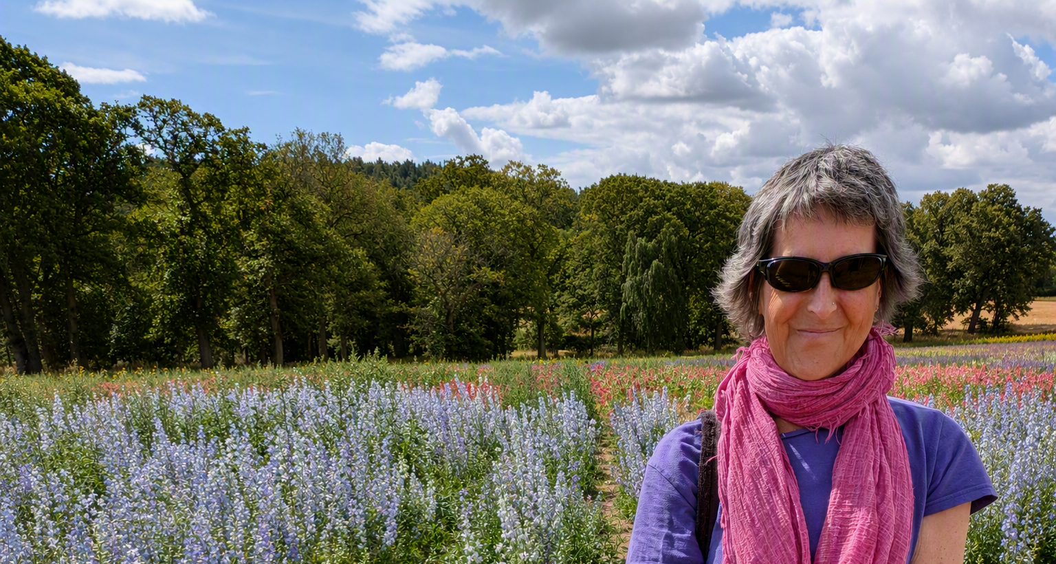 Julie of Joyfully Wellthy standing in front of a field of flowers