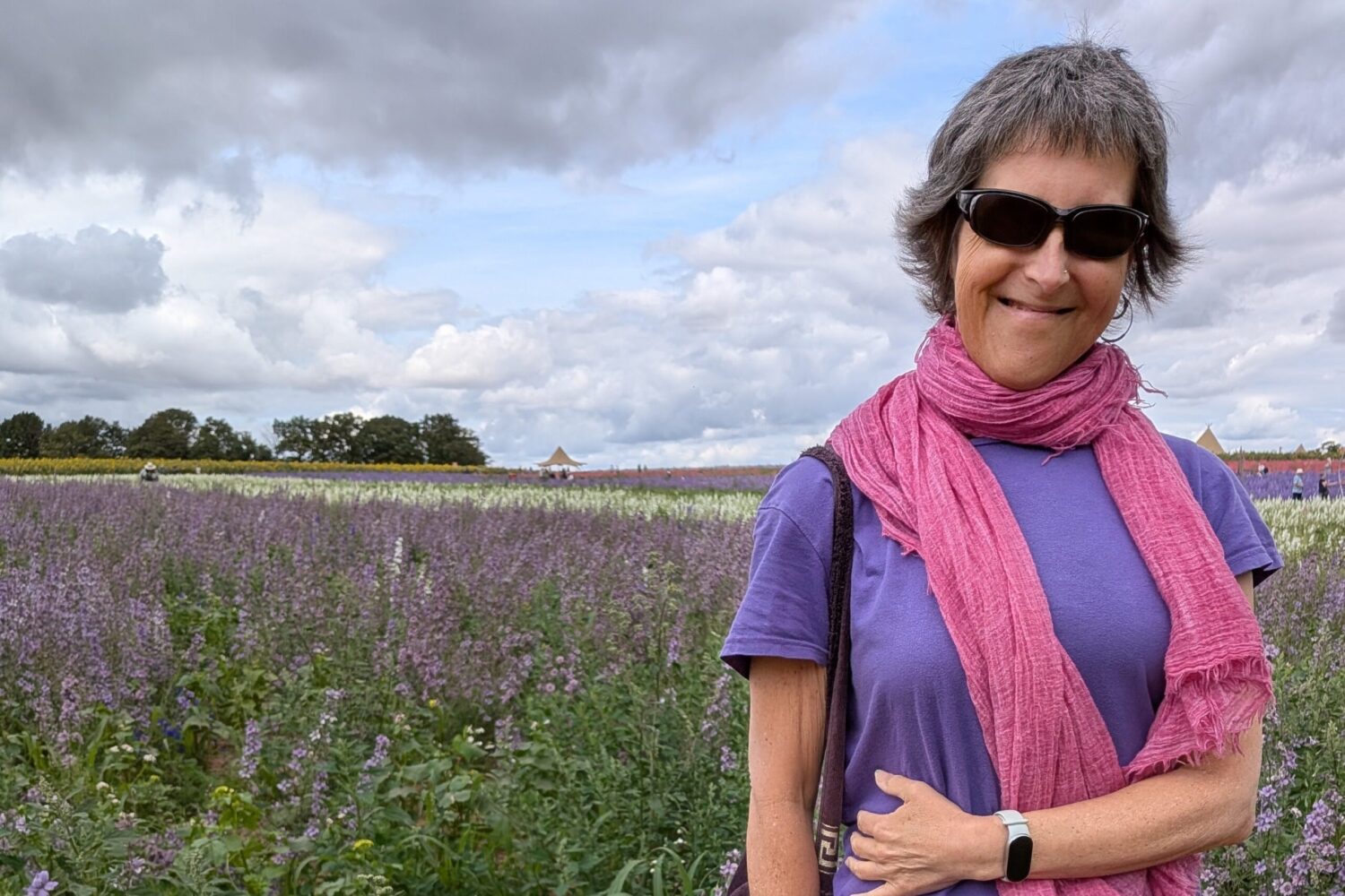 A smiling Julie standing in a field of flowers